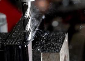 Bridgeport CNC end mill finishing a stack of steel plate with metal filings chips and light smoke photo