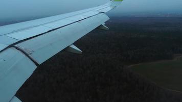 aile d'avion depuis la fenêtre, forêt verte. descente avant atterrissage video