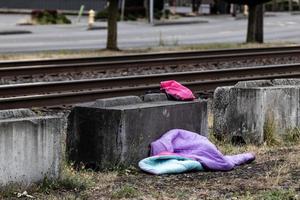 Homeless childs sleeping bag next to a railroad track concrete block photo