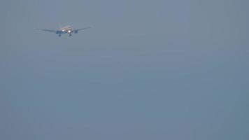 Footage long shot of a passenger airliner descending for landing at dusk. Airplane in cloudy sky, front view. Tourism and aviation concept video