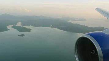 vista desde la ventana del avión a la isla de phuket. mar y colinas, paisaje paradisíaco de una isla tropical. concepto de turismo y viajes. video