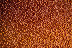 Glistening rain drops on an orange metal sheet photo