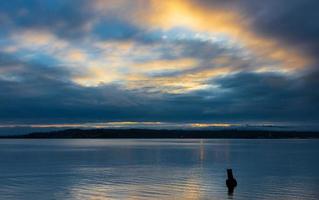 Cloudy blue golden yellow sky sunrise sunset over water photo