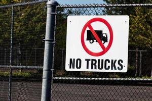 White no trucks sign on a chain link fence photo