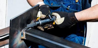 Welding steel worker breaking away slag from perfect spiral welds photo