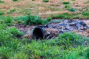 Overflow water drainage pipe emerging from the ground photo