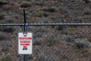 No trespassing authorized personnel sign on a chain link barbed wire fence photo