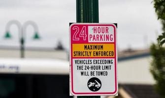 Señal de estacionamiento estrictamente aplicada las 24 horas en un poste verde foto