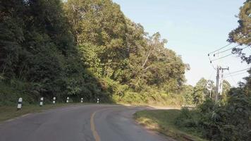 visão frontal do motorista enquanto viaja na estrada local cercada por pinheiros floresta de terras altas no horário do pôr do sol de inverno video