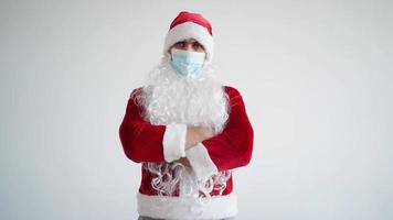 de kerstman claus in een medisch masker looks Bij de camera met een echt kijken Aan een wit achtergrond. Kerstmis quarantaine en coronavirus concept. nieuw jaar pandemie. video