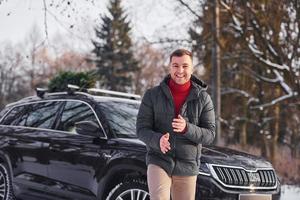 Front view. Man with little green fir is outdoors near his car. Conception of holidays photo