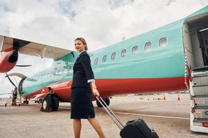 mujer joven con equipaje está al aire libre cerca del avión foto