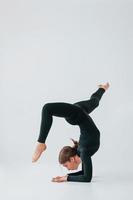 Difficult exercises. Young woman in sportive clothes doing gymnastics indoors photo