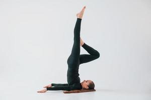 Practice routine. Young woman in sportive clothes doing gymnastics indoors photo