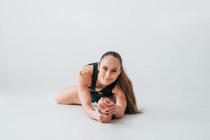 centrado en los ejercicios. mujer joven en ropa deportiva haciendo gimnasia en el interior foto