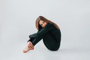 On the floor. Young woman in sportive clothes doing gymnastics indoors photo