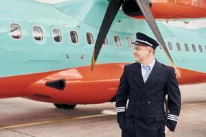 Experienced pilot in uniform standing outside near plane photo