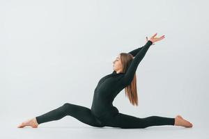 In black sportive clothes. Young woman doing gymnastics indoors photo