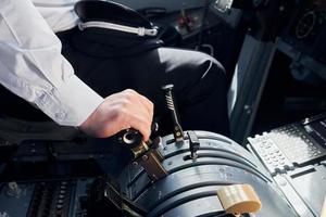 Side view. Pilot in formal wear sits in the cockpit and controls airplane photo