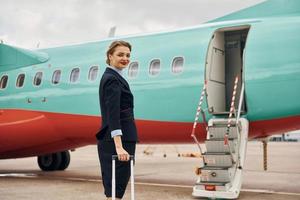 mujer joven con equipaje está al aire libre cerca del avión foto