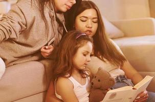 Female lesbian couple with little daughter spending time together at home photo