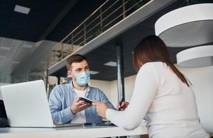 la mujer recibe ayuda del trabajador. joven con camisa blanca y chaqueta azul está adentro foto