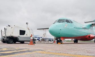 Vehicle nearby. Turboprop aircraft parked on the runway at daytime photo