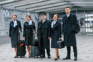 Aircraft crew in work uniform is together outdoors in the airport photo