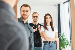 hombre con cámara haciendo fotos en el espejo de sí mismo y de sus amigos