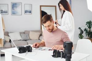 Two photographers in casual clothes is working indoors at daytime photo