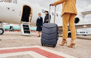 Airplane crew leads woman in yellow clothes inside of a plane photo