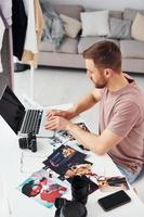 Photographer in casual clothes is working indoors at daytime photo