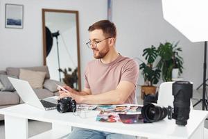 Photographer in casual clothes is working indoors at daytime photo