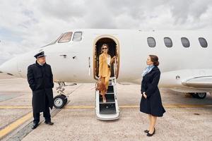 el aterrizaje está hecho. la tripulación del avión lleva a una mujer vestida de amarillo desde un avión foto