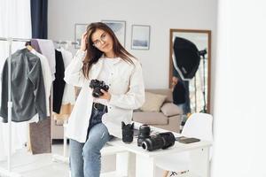 Female photographer in casual clothes is working indoors at daytime photo