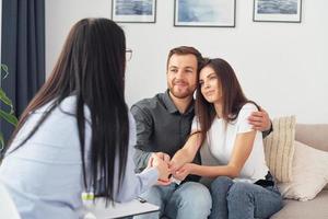 Couple is sitting on the sofa and working with female psychologist photo