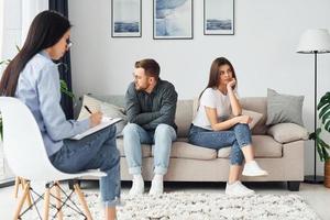 la pareja está sentada en el sofá y trabajando con una psicóloga foto