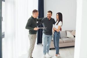 Salesman helps young couple in choosing an apartment. Conception of business and rent photo