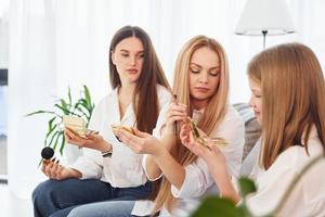 Teaching how to do make up. Young mother with her two daughters at home at daytime photo