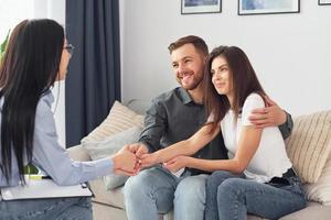 Couple is sitting on the sofa and working with female psychologist photo