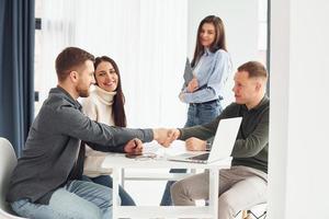 Four people works in the office by sitting by the table indoors photo