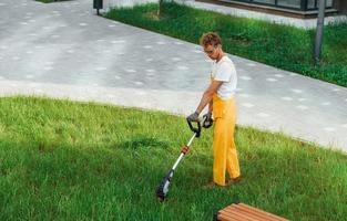 Outdoors in the yard. Man cut the grass with lawn mover photo