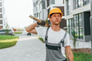 Walking outdoors. Young man working in uniform at construction at daytime photo