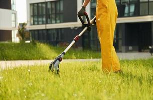 Close up view. Man cut the grass with lawn mover outdoors in the yard photo