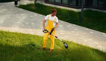 Distant view. Man cut the grass with lawn mover outdoors in the yard photo