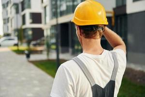 Rear view. Young man working in uniform at construction at daytime photo