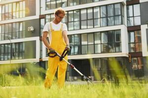 Busy day. Man cut the grass with lawn mover outdoors in the yard photo