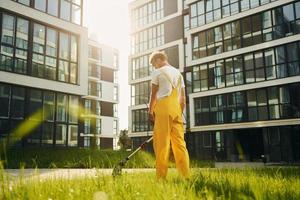 Busy day. Man cut the grass with lawn mover outdoors in the yard photo