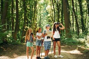 Searching for the path. Kids strolling in the forest with travel equipment photo