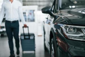 Partical view. Man in formal clothes is with luggage indoors near the car photo